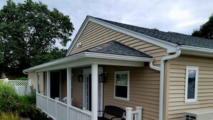 A single-story house with a covered porch, a fenced yard, and a small garden with flowers. - Cityline suite Three miles to PC, RIC, BROWN, JWU, &RISD (North Providence)