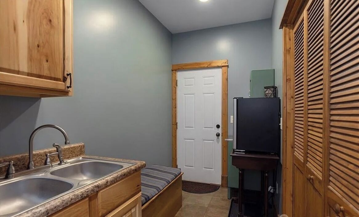 A compact kitchen with wooden cabinets, a double sink, and a small refrigerator.