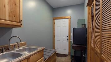A compact kitchen with wooden cabinets, a double sink, and a small refrigerator.