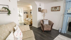 A living room with a sofa, a chair, a lamp, and a fireplace. - Penrallt (Cemaes Bay)