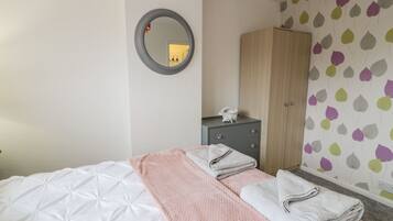 Una habitación de hotel con cama, armario, mesita de noche y espejo.