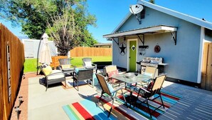A backyard with a barbecue grill, outdoor furniture, and a colorful striped rug. - Tranquil 3 Bedroom, 2 Bath Home Near Scenic River Walk! (Baker City)