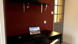 Et værelse med et sort skrivebord, en bærbar computer og en hvid stol.