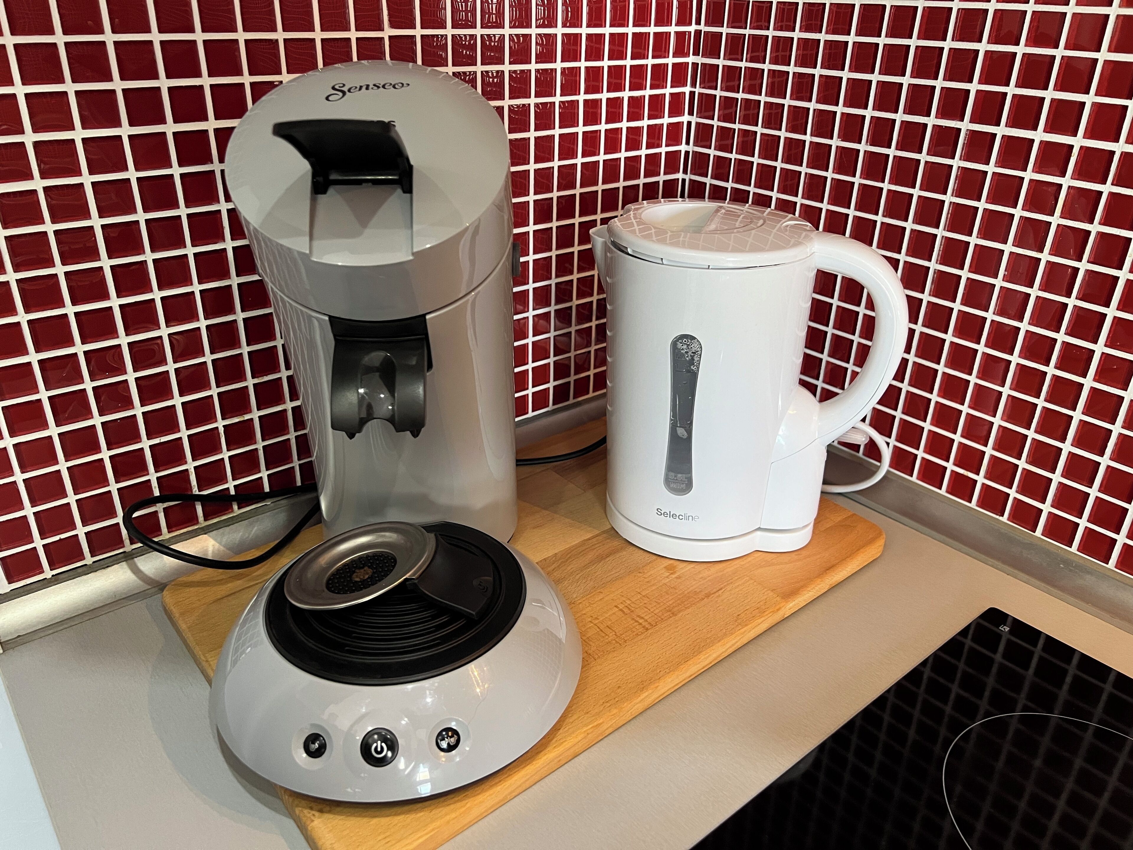 Een koffiezetapparaat en een mok op een houten plank.