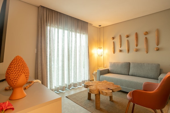 Una sala de estar moderna con un sofá gris, una mesa de centro de madera y un sillón naranja.