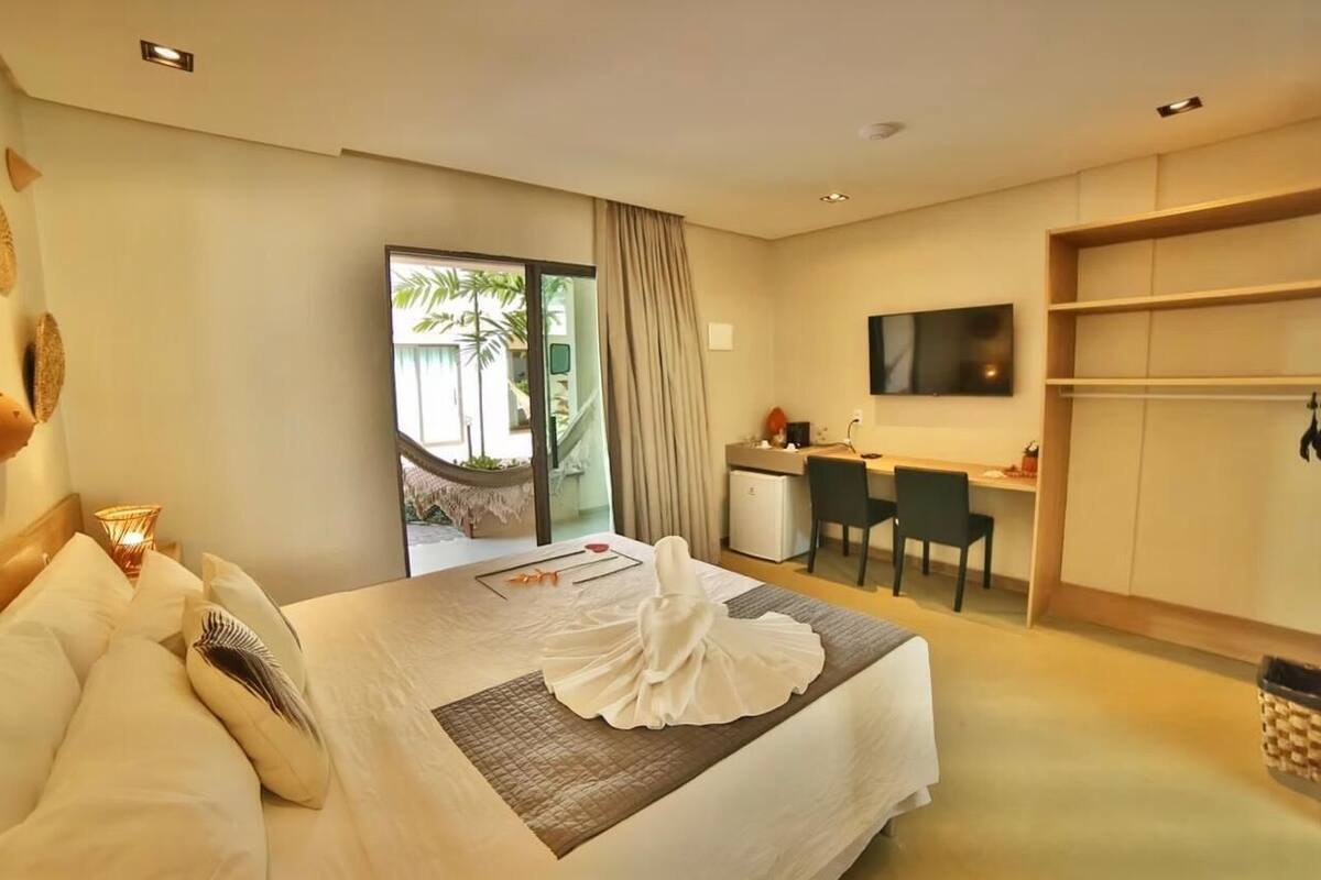 Een hotelkamer met een bed, bureau, stoel, televisie en uitzicht op het omliggende landschap.
