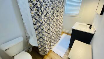 Een bad/douchecombinatie, een haardroger, handdoeken, zeep