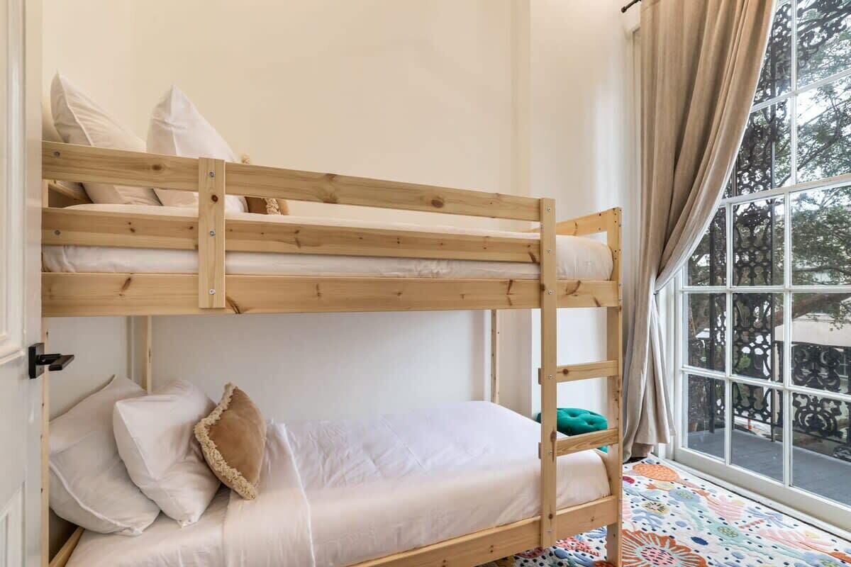 Uma cama beliche com roupa de cama branca e um tapete colorido estampado.