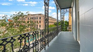 Ein Balkon mit aufwendigen schwarzen Geländern, Blick auf ein Backsteingebäude und einem strahlend blauen Himmel.