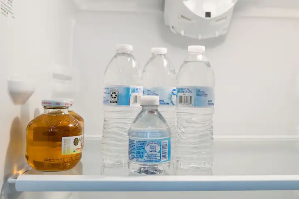 A refrigerator shelf with a bottle of orange juice and three water bottles.