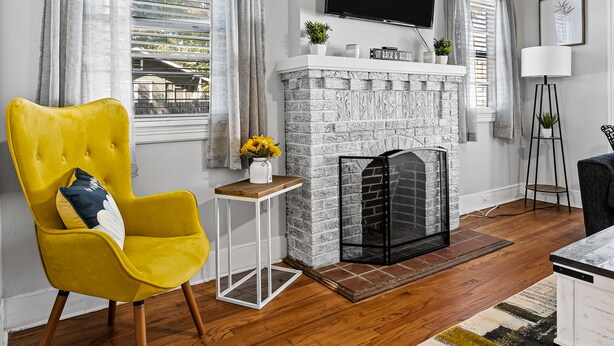 A living room with a yellow armchair, a fireplace, a television, and a floor lamp.
