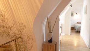 A hallway with a wooden floor, a white wall, and a plant in a vase. - charming medieval house 3* (Baden)