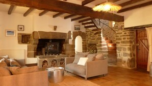 A cozy living room with a fireplace, stone walls, a wooden ceiling, and a staircase. - charming medieval house 3* (Baden)