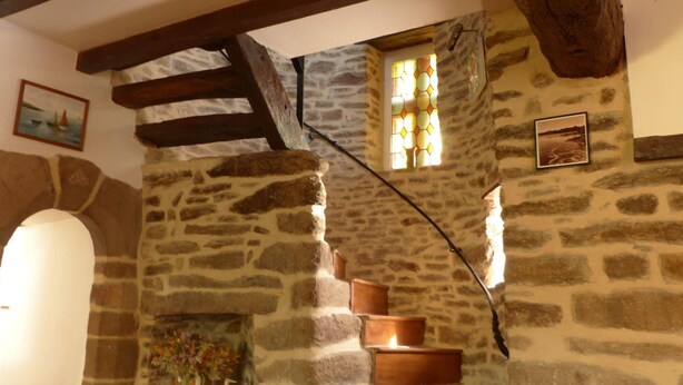 A stone interior with a fireplace, wooden beams, and a small window with stained glass. - charming medieval house 3* (Baden)