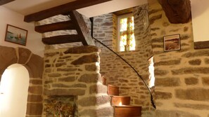 A stone interior with a fireplace, wooden beams, and a small window with stained glass. - charming medieval house 3* (Baden)
