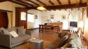 A living room with a sofa, a coffee table, a dining area with a table and chairs, a TV, and a lamp. - charming medieval house 3* (Baden)