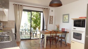 A kitchen with a dining area, a sliding glass door to the outdoors, and a microwave above the oven. - charming medieval house 3* (Baden)
