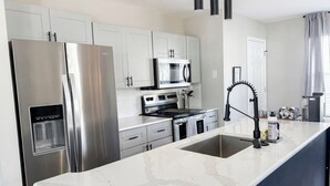 A modern kitchen with white cabinets, stainless steel appliances, a marble countertop, and pendant lighting. - Few Mins to Ballantyne-Pet Friendly-1 Level Home (Pineville)
