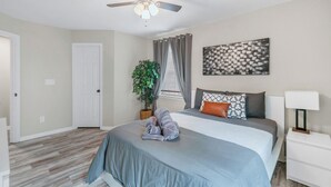 A bedroom with a bed, a ceiling fan, a potted plant, a nightstand, and a wall art piece. - Few Mins to Ballantyne-Pet Friendly-1 Level Home (Pineville)