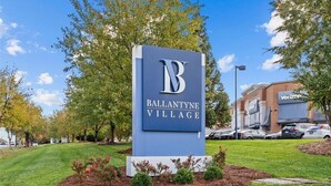 A sign for Ballantyne Village with a clear blue sky and trees in the background. - Few Mins to Ballantyne-Pet Friendly-1 Level Home (Pineville)
