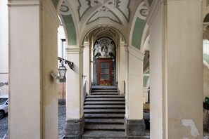A staircase leading to a door with a decorative archway, a street lamp, and a parked car.