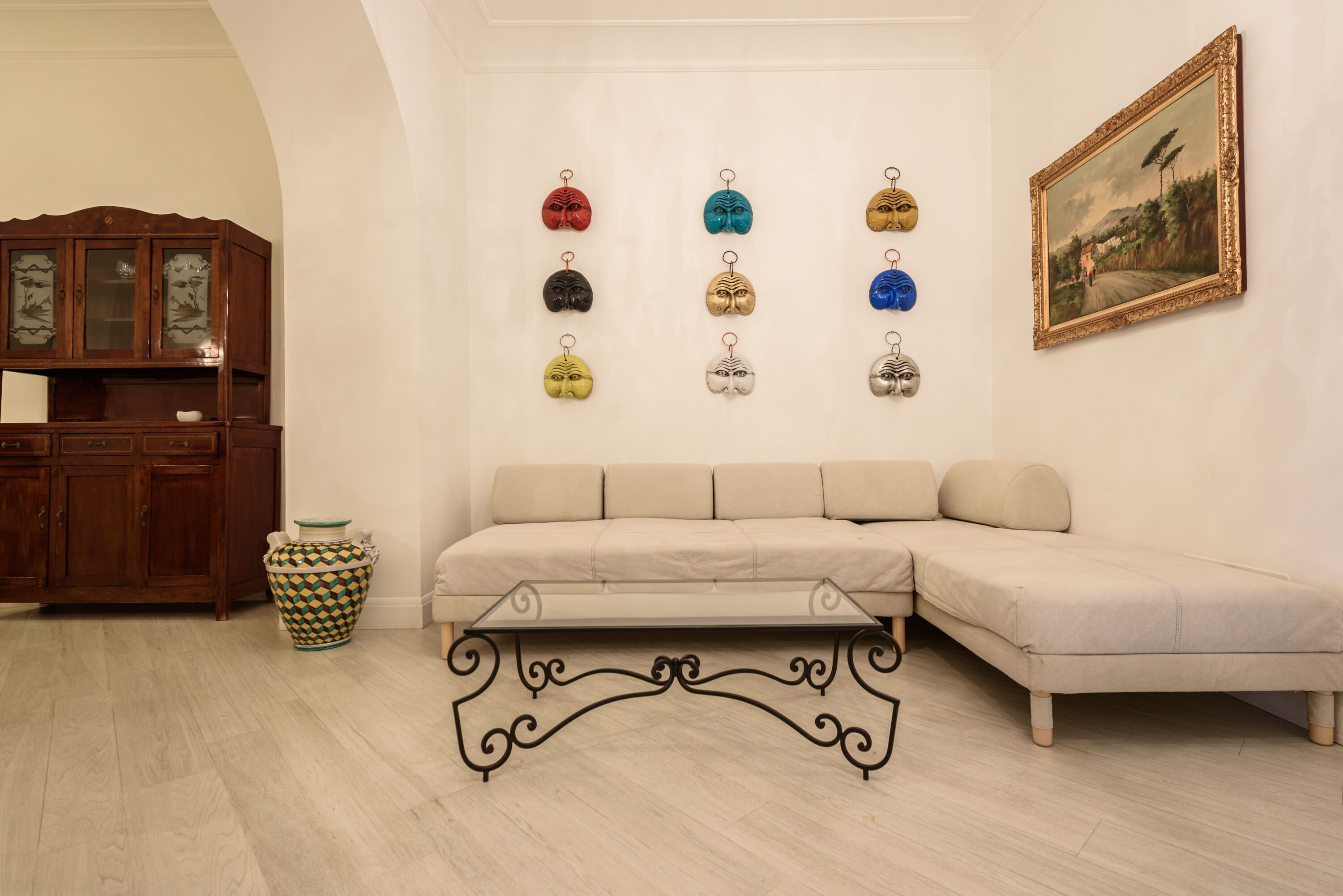 A living room with a beige sofa, a wooden cabinet, a decorative vase, and a wall-mounted picture frame.
