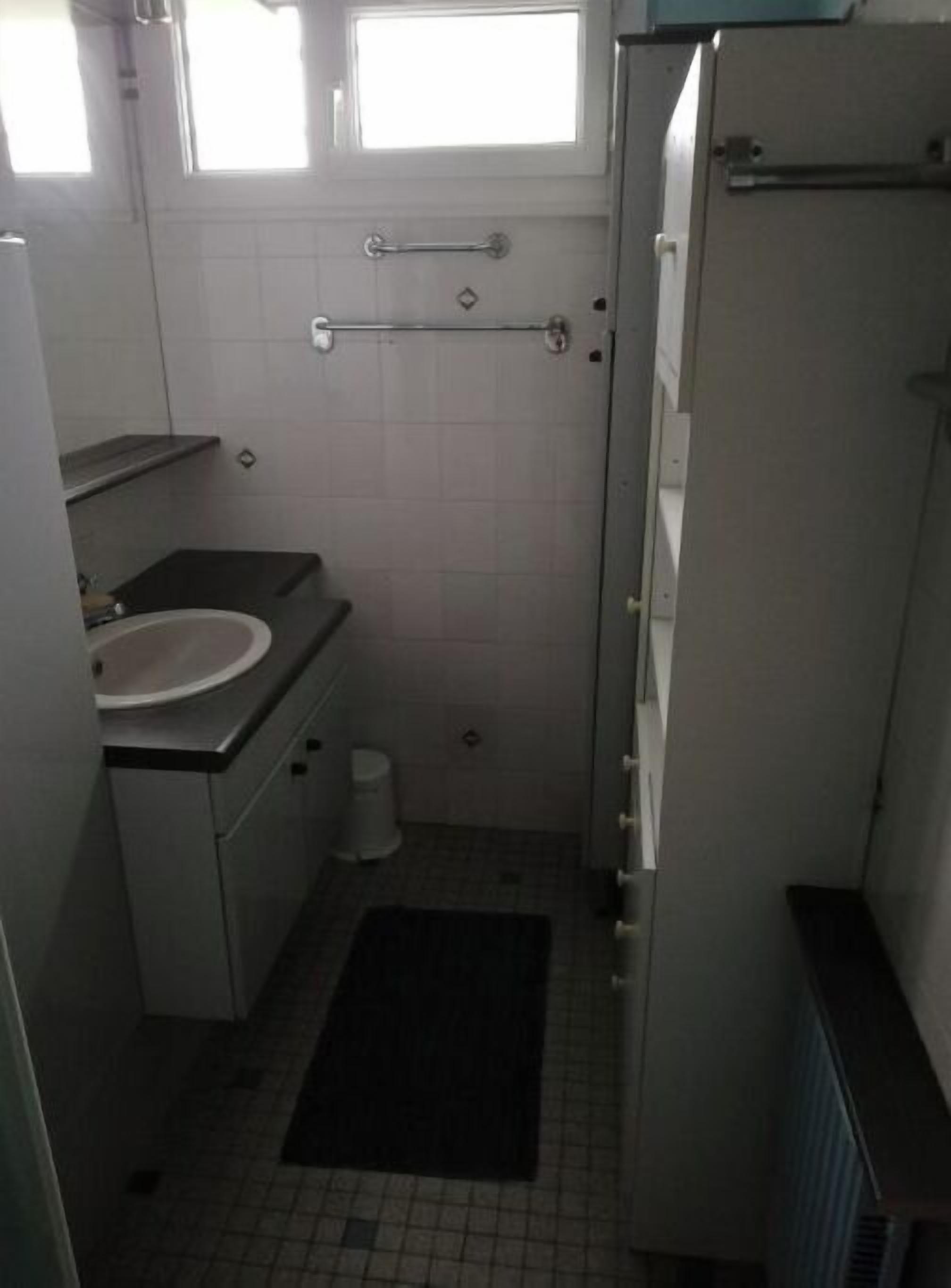 A small, compact bathroom with a sink, toilet, and a towel rack.