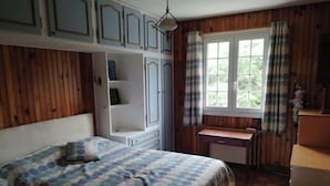 A bedroom with a bed, a desk, and a window.