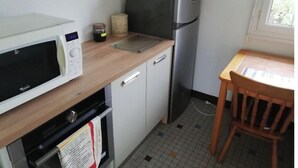A compact kitchen with a microwave, refrigerator, and wooden countertop.