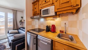 Una cucina compatta con mobili in legno, un forno a microonde, un lavandino e una lavastoviglie.