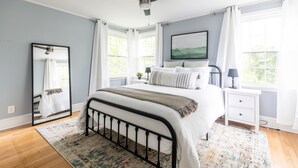 A bedroom with a bed, a nightstand, a mirror, and a ceiling fan.