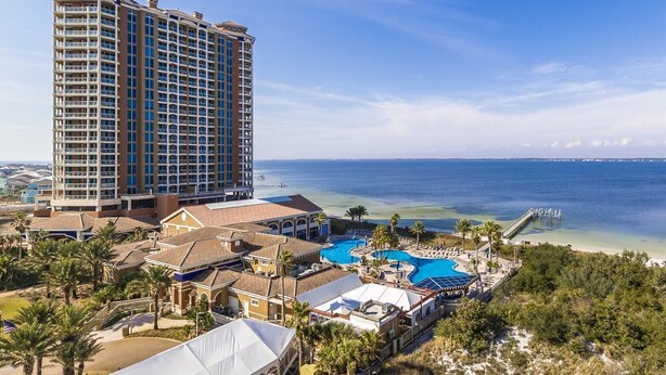 A high-rise hotel with a large pool area, beachfront access, and a view of the ocean.