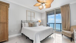 A bedroom with a bed, a nightstand, a chair, a wooden wardrobe, and a balcony with a view.