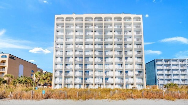 Ett hotell med flera våningar, en enhetlig fasad, balkonger och ett läge vid stranden.