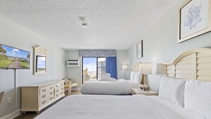 Ett hotellrum med en stor säng, en byrå, ett skrivbord och utsikt över staden.