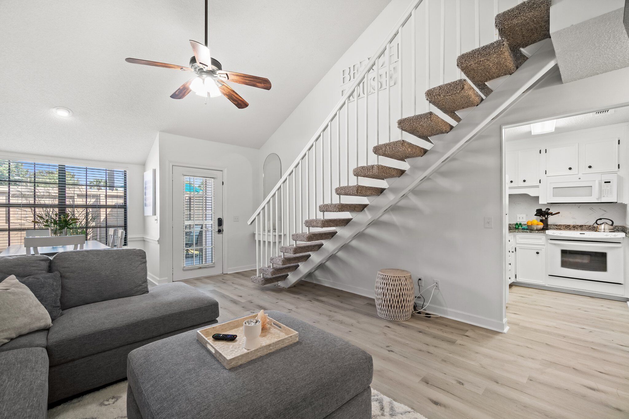 Ein modernes Wohnzimmer mit einem grauen Sofa, einem Holztisch und einer Treppe mit einem markanten Design.