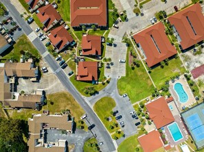 Luchtbeeld van een woongebied met meerdere huizen, een zwembad en een tennisbaan.