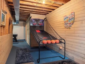 A small indoor basketball court with a net, a few basketballs, and a wooden wall with license plates.