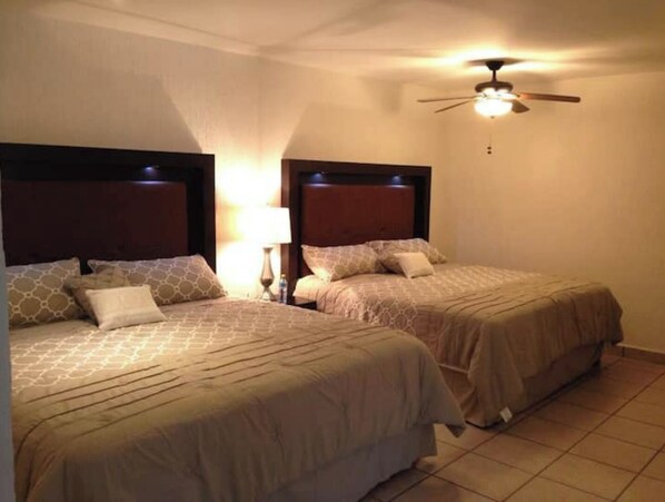 Two single beds with wooden headboards, a ceiling fan, and a nightstand with a lamp between them. - My Depa Mango In the Center of Cd. valleys (Ciudad Valles)