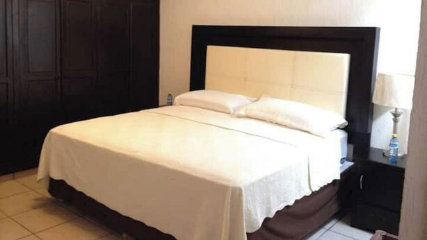 Een hotelkamer met een groot bed, een donkerhouten garderobe en een plafondventilator.
