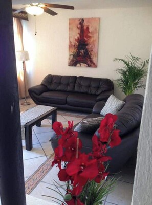Relax in the stylish living room with a sofa, armchair, and coffee table, accompanied by a beautiful painting of the Eiffel Tower and a potted plant.