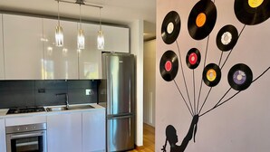Una cocina moderna con electrodomésticos de acero inoxidable, iluminación colgante e instalación artística de discos de vinilo.
