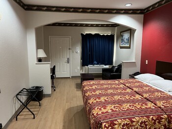A multi-story motel with a central entrance, balconies, and a parking lot. at Scott Inn Suites - Downtown Houston