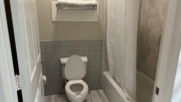 A bathroom with a toilet, a shower, and a towel rack.