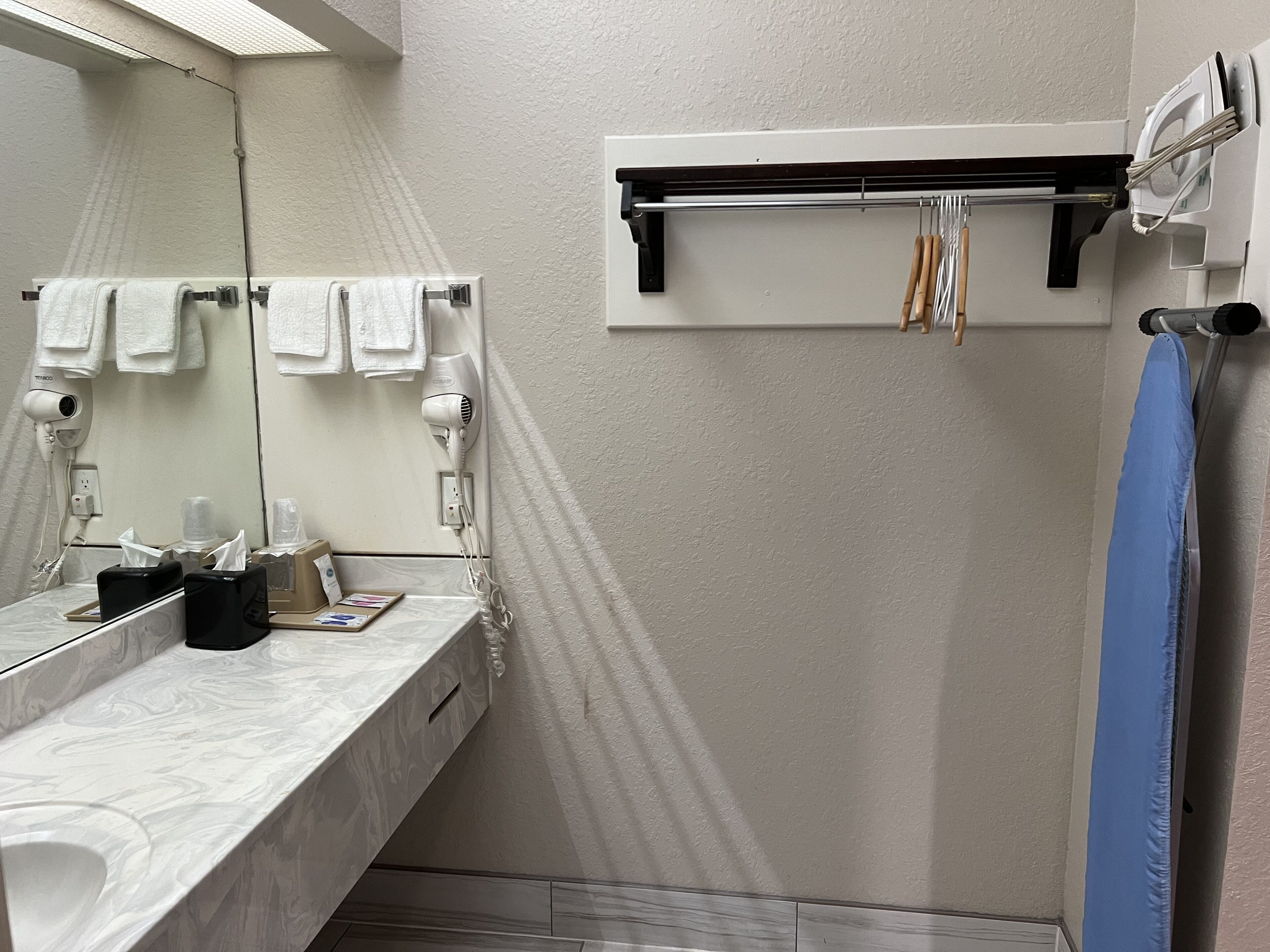 A bathroom with a marble sink, a towel rack with white towels, a hairdryer, and a blue shower curtain.
