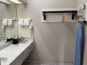 A bathroom with a marble sink, a towel rack with white towels, a hairdryer, and a blue shower curtain. - Scott Inn Suites - Downtown Houston (Houston)