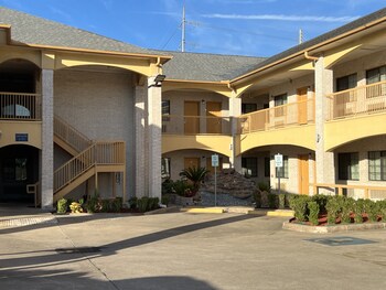 A building with a brick facade, a covered entrance, and a sign indicating parking at your own risk. at Scott Inn Suites - Downtown Houston