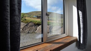A window with a view of a grassy landscape and a hill.