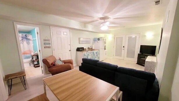 A living room with a wooden table, a dark sofa, and a television. - OBX~Beach~Sunsets~Bike Path~Mini Golf~Lighthouses~Shops~Walking Distance~Sunrise (Kill Devil Hills)