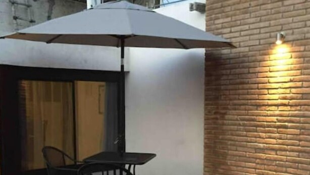 A patio area with a table and chairs, an umbrella, and a potted plant. - My Depa Vanilla. In the heart of Cd. Valleys. (Ciudad Valles)
